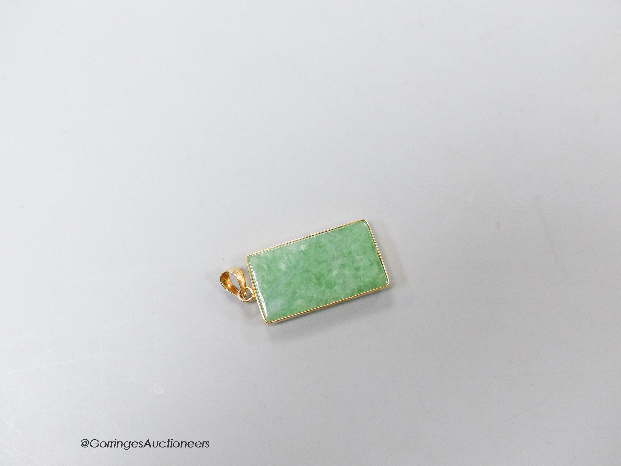 A Chinese yellow metal mounted jadeite rectangular pendant, with Chinese characters, 25mm, gross 4.7 grams.